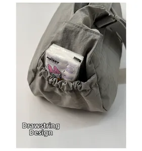 Detail view of functional drawstring side pocket on gray nylon crossbody bag