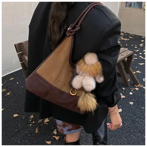 Detail of tan matte tote bag with rope handles and plush charm on female model