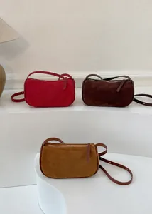 Dettaglio borse a bauletto in pelle scamosciata rossa, marrone e kaki con tracolla