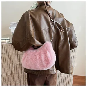 Detail of pink faux fur crossbody bag with silver chain strap shown on a model