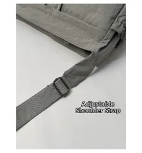 Detail view of the adjustable shoulder strap and metal buckle on the nylon crossbody bag