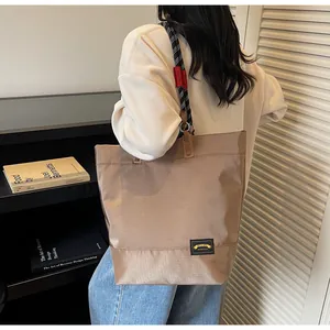 Detail of khaki tote bag with woven texture, rope shoulder strap and branded label