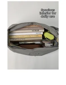 Internal capacity of the grey nylon crossbody bag showing books and daily essentials