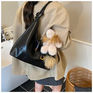 Detail of black matte tote bag with knotted shoulder strap and plush teddy bear charms