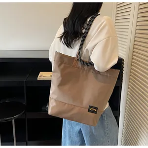 Detail of khaki tote bag featuring woven rope handles and minimalist patch accent