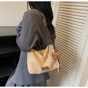 Détail du sac cabas kaki vintage avec bandoulières en cuir brun et pendentif ours