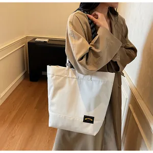 White large capacity tote bag with checkerboard strap shown styled with a trench coat