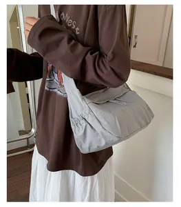 Detailed side view of a light grey nylon crossbody bag showing drawstring and texture