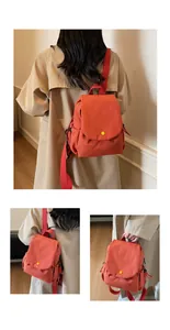 Side view of red canvas backpack featuring flap closure and distinctive yellow button detail
