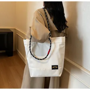 Detail view of the large white tote bag featuring woven rope straps and red accent detail