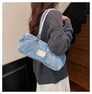 Cylindrical light blue washed denim shoulder bag styled with casual knitwear and skirt