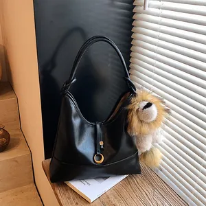 Matte black leather tote bag with unique lion head plush charm and gold buckle detail