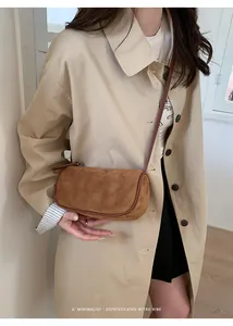 Borsa a tracolla cilindrica in camoscio marrone indossata con un trench beige