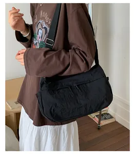Detail of black nylon crossbody bag featuring drawstring zipper and adjustable wide strap