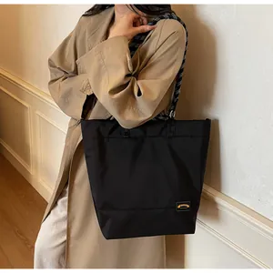 Detail of black nylon tote bag featuring black and white woven rope shoulder straps