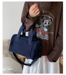 Blue cylindrical travel tote bag shown on model with adjustable strap and handles