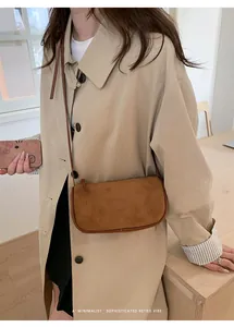 Borsa a tracolla marrone retrò abbinata a un trench beige in stile minimalista