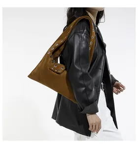 Dettaglio della borsa tote in pelle scamosciata marrone con occhielli e borchie
