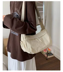 Detailed view of beige nylon crossbody bag featuring drawstring pockets and wide strap