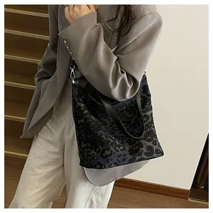 Detailed view of leopard print bucket bag with leather handles and metal hardware