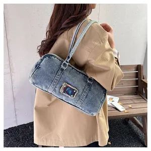Detail of vintage washed blue denim tote bag with metallic studs and shoulder strap