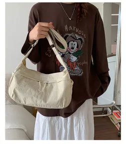 Beige nylon crossbody bag detail with adjustable canvas strap and zipper on casual outfit