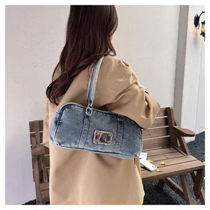 Detail of blue washed denim shoulder bag with metal logo patch on casual tote