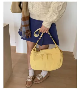 Detail shot of a yellow nylon crossbody bag featuring an external zipper pocket on a model
