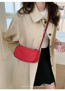 Borsa a tracolla cilindrica rossa in pelle scamosciata opaca con un trench coat beige chic