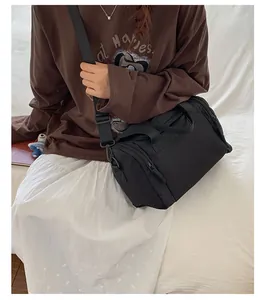 Model wearing a large black travel duffel bag with dual handles and adjustable shoulder strap