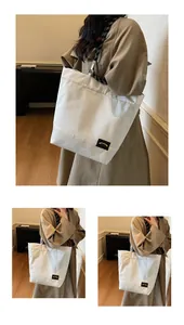 Detail view of white canvas tote bag with a stylish black and white striped shoulder strap