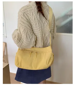 Detail of yellow nylon crossbody bag worn by model showing its large capacity and style