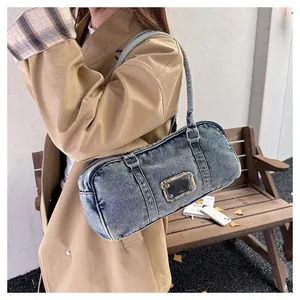 Close-up of retro washed denim cylinder shoulder bag with square metallic emblem