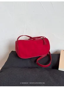 Dettaglio di una borsa a cilindro rossa in pelle scamosciata con finiture in pelle liscia