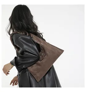 Dettaglio della borsa tote marrone scuro con occhielli argento e giacca in pelle