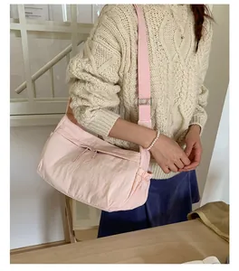 Detail of pink nylon shoulder bag showing zipper pockets and adjustable wide strap