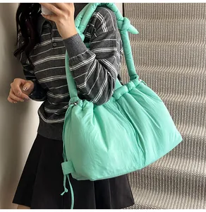 Close-up of a mint green puffer tote bag featuring soft nylon pleats and padded straps