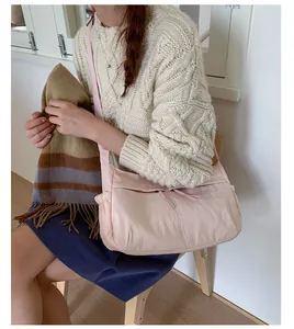 Detail of light pink nylon crossbody bag with adjustable strap and waterproof fabric texture