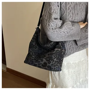 Detailed view of leopard print bucket bag with long black shoulder strap on model