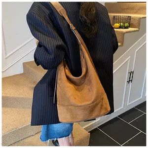 Close-up of a brown suede bucket bag with textured finish and wide shoulder strap