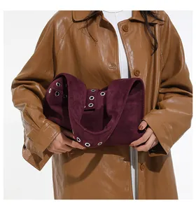 Dettagli di rivetti vintage e occhielli metallici su una borsa a tracolla in pelle scamosciata