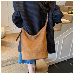 Brown suede bucket bag for women shown as a stylish shoulder bag in a casual setting