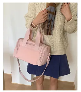 Detailed shot of a pale pink travel bag showing nylon texture and adjustable strap