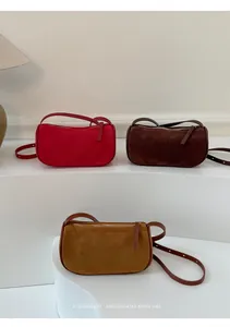 Tre borse a mano minimaliste in pelle scamosciata rossa, marrone e caramello su stand