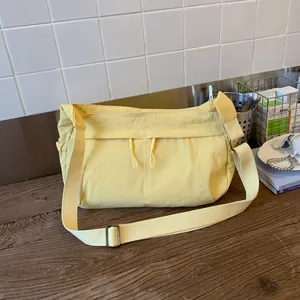 Close-up of yellow nylon crossbody bag with dual drawstring zipper pockets on a table