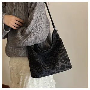 Close-up of leopard print bucket bag paired with a grey knit sweater and lace skirt