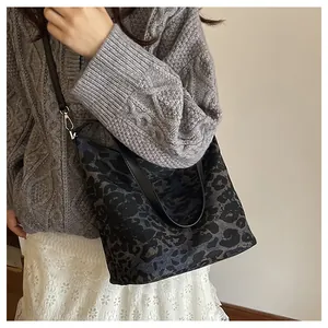 Close-up of a leopard print bucket bag with black leather straps and silver hardware