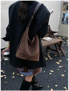 Outdoor view of a dark brown suede hobo bag with adjustable strap in an autumn setting
