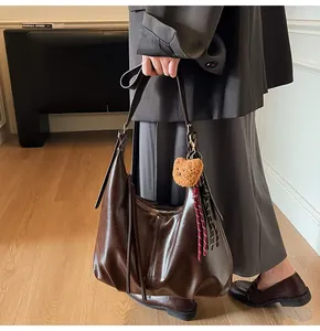 Detail of dark brown vintage faux leather tote with tassel zipper and plush bear charm