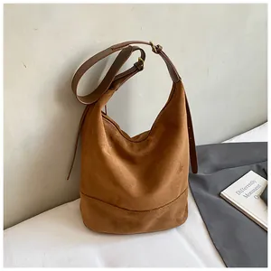 Detailed close-up of brown suede hobo bag texture with adjustable leather strap and stitching